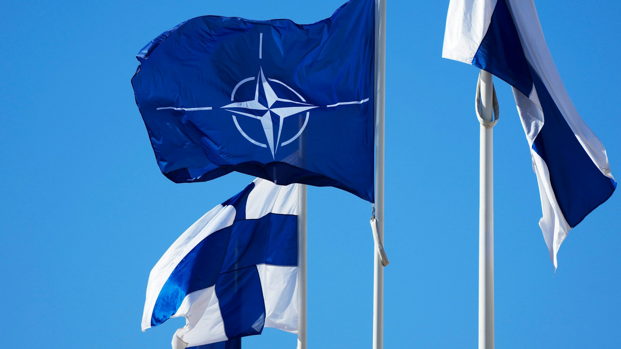 04.04.2023, Finnland, Helsinki: Die Nato-Flagge (M) und die finnische Flagge flattern über dem Gebäude des finnischen Außenministeriums.