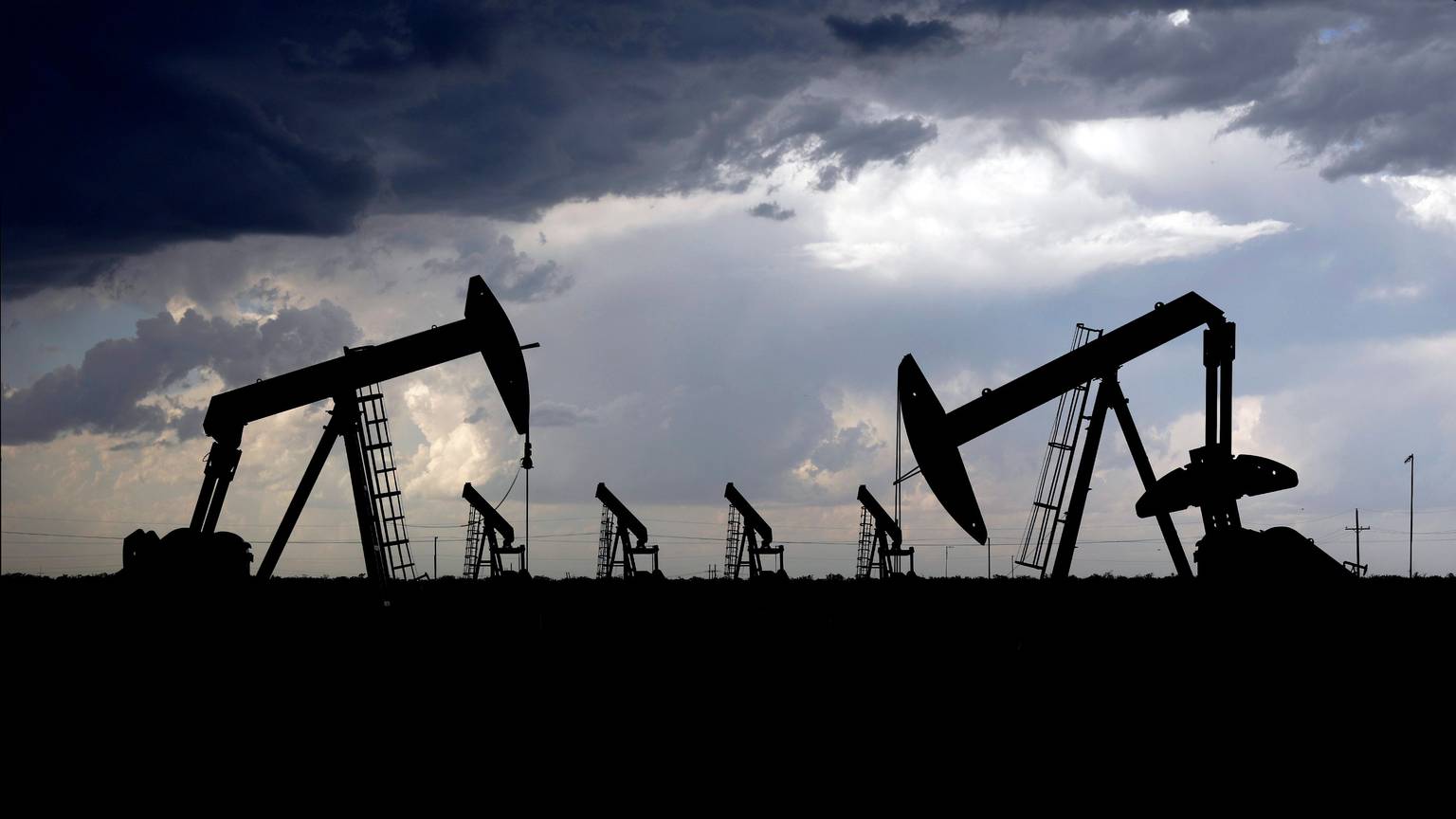 Ein Gewitter zieht zwischen Midland und Odessa, Texas, direkt hinter einer Reihe von Tiefpumpen an einem Ölfeld vorbei.