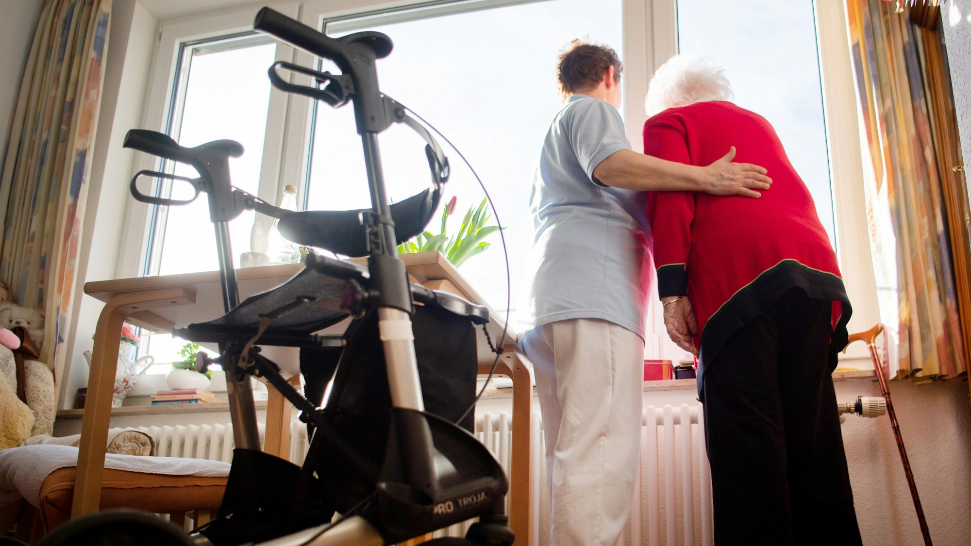 ARCHIV - 15.01.2020, Baden-Württemberg, Böblingen: Eine Pflegerin (l) und eine Bewohnerin des Pflegeheims schauen zusammen aus einem Fenster im Wohnbereich des Pflegeheims. (zu dpa «Spahn will langfristig Pflegebedürftige finanziell entlasten ») Foto: Tom Weller/dpa +++ dpa-Bildfunk +++