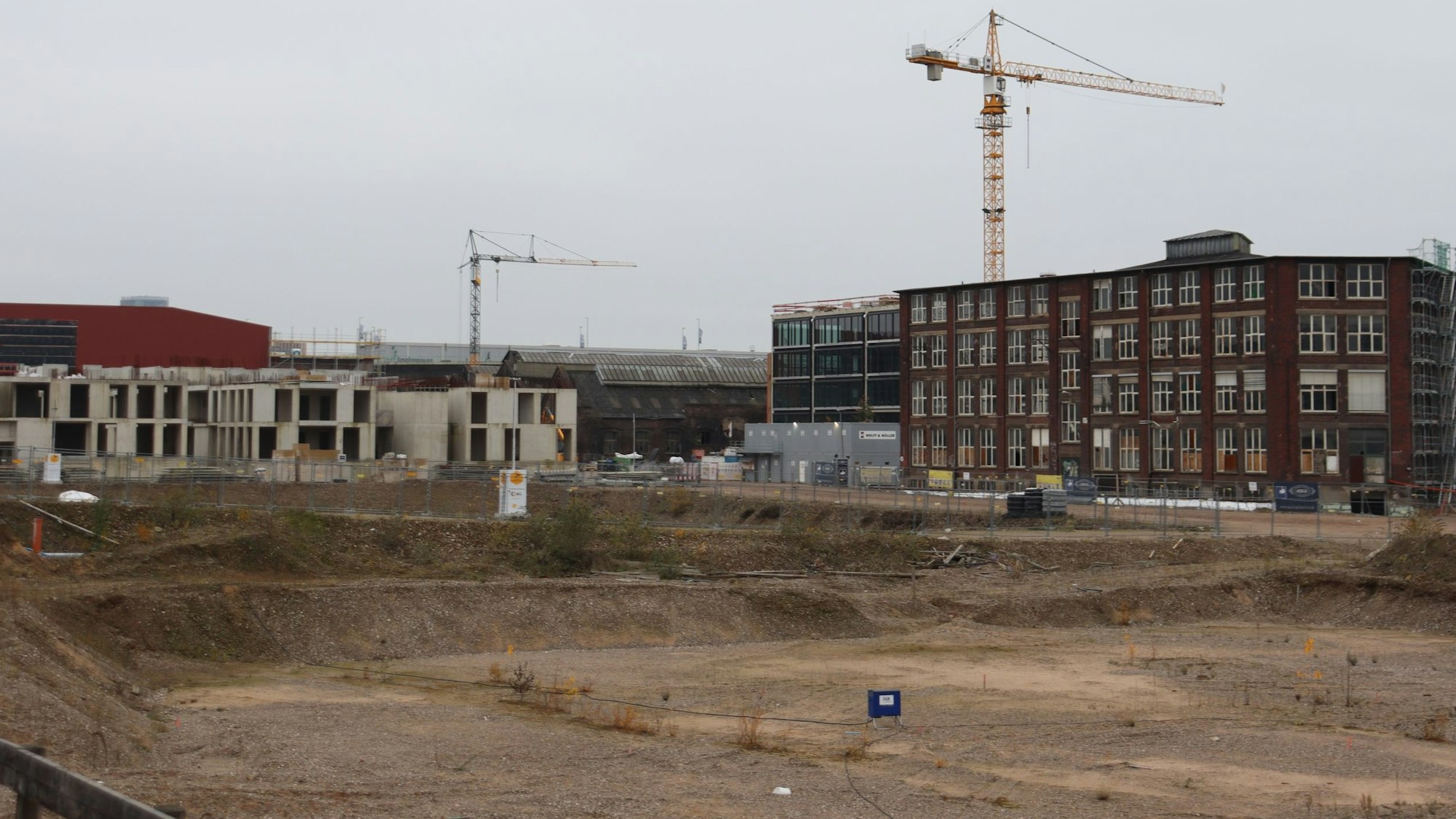 Zwei Kräne und Bauruinen umgeben ein Lehmloch im Mülheimer Süden