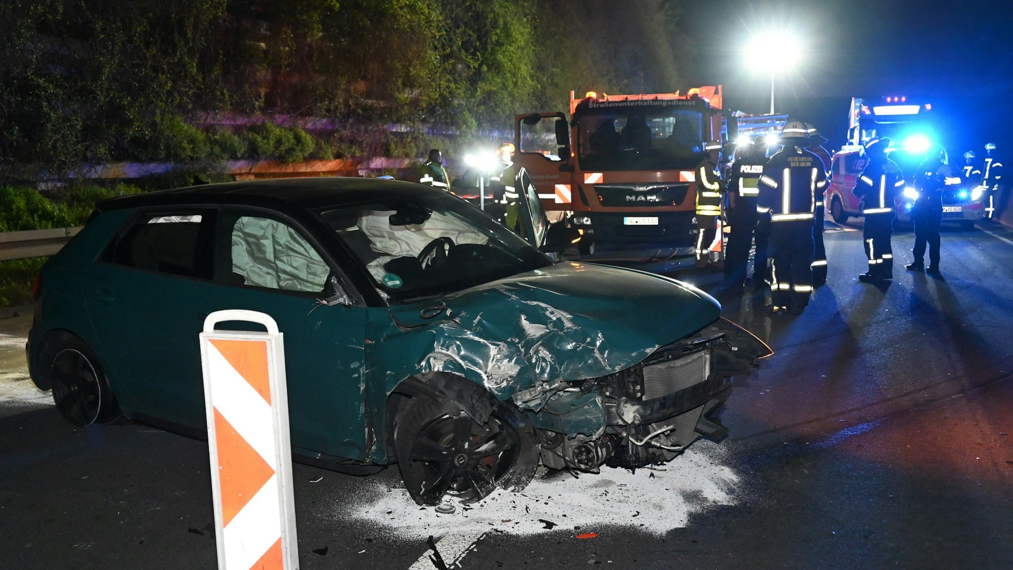 Ein demoliertes Auto steht auf einer Autobahn. Rettungskräfte stehen daneben.