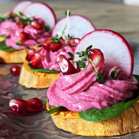 Auf einer Süßkartoffelscheibe ist ein Rote-Bete-Frischkäse-Türmchen aufgespritzt.