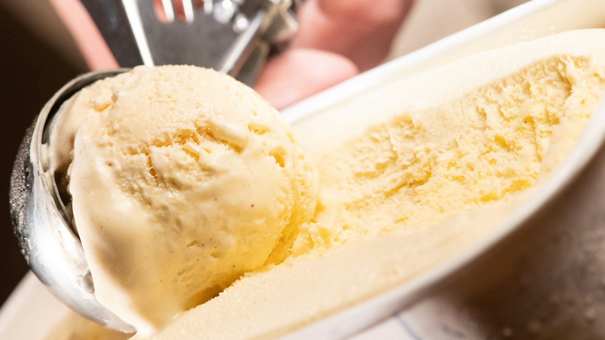 Vanilleeis wird aus einer Verpackung portioniert.