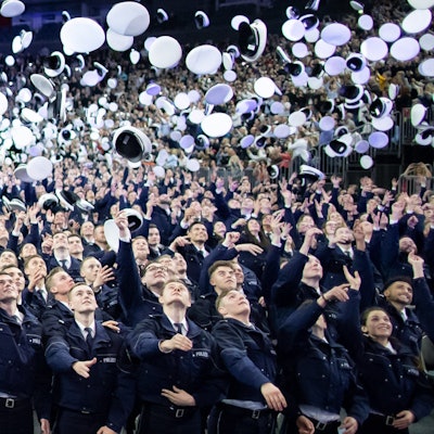 ARCHIV - 03.04.2019, Nordrhein-Westfalen, Köln: Kommissaranwärter werfen nach ihrer Vereidigung die Mützen hoch.