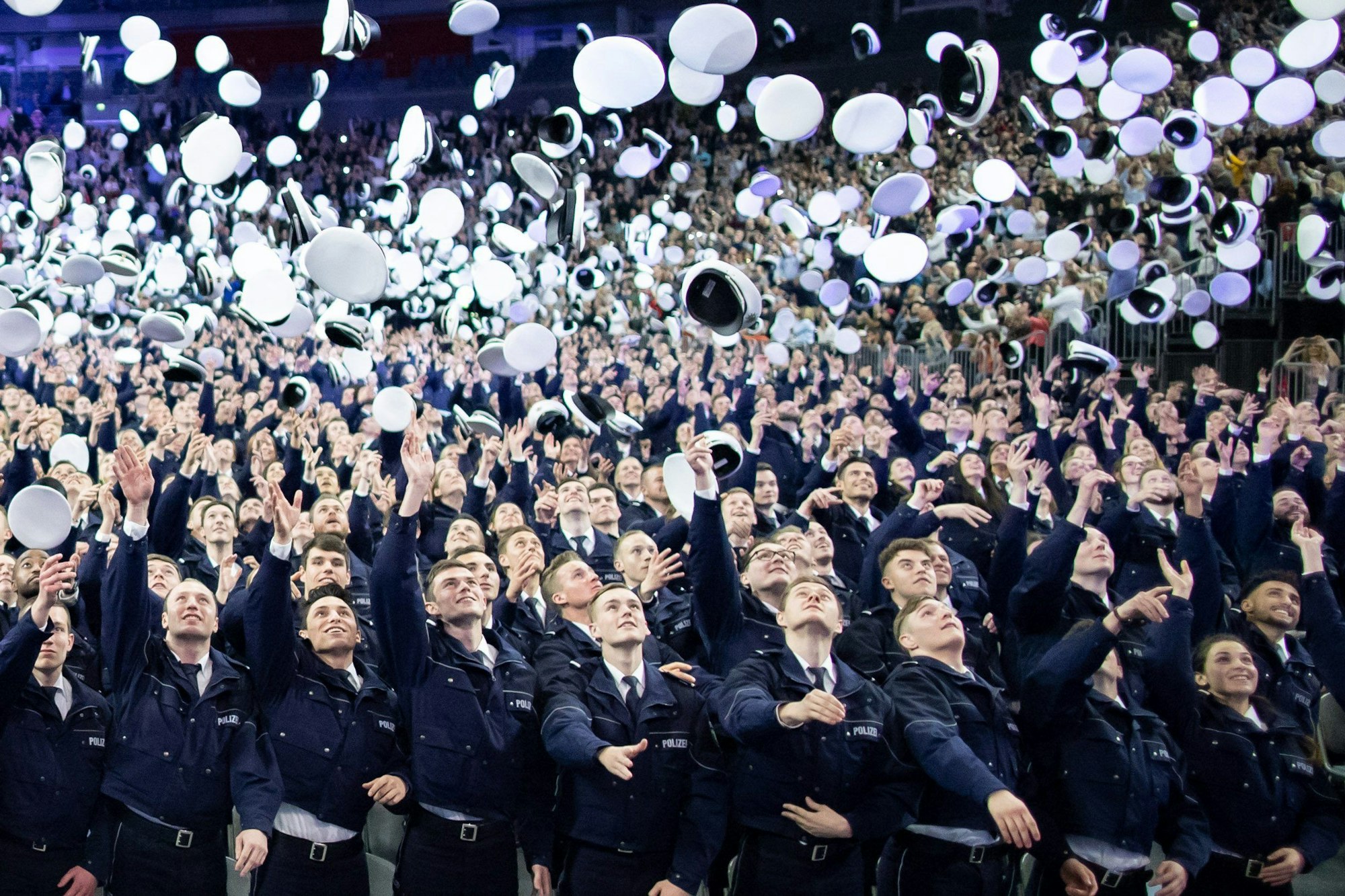 ARCHIV - 03.04.2019, Nordrhein-Westfalen, Köln: Kommissaranwärter werfen nach ihrer Vereidigung die Mützen hoch.