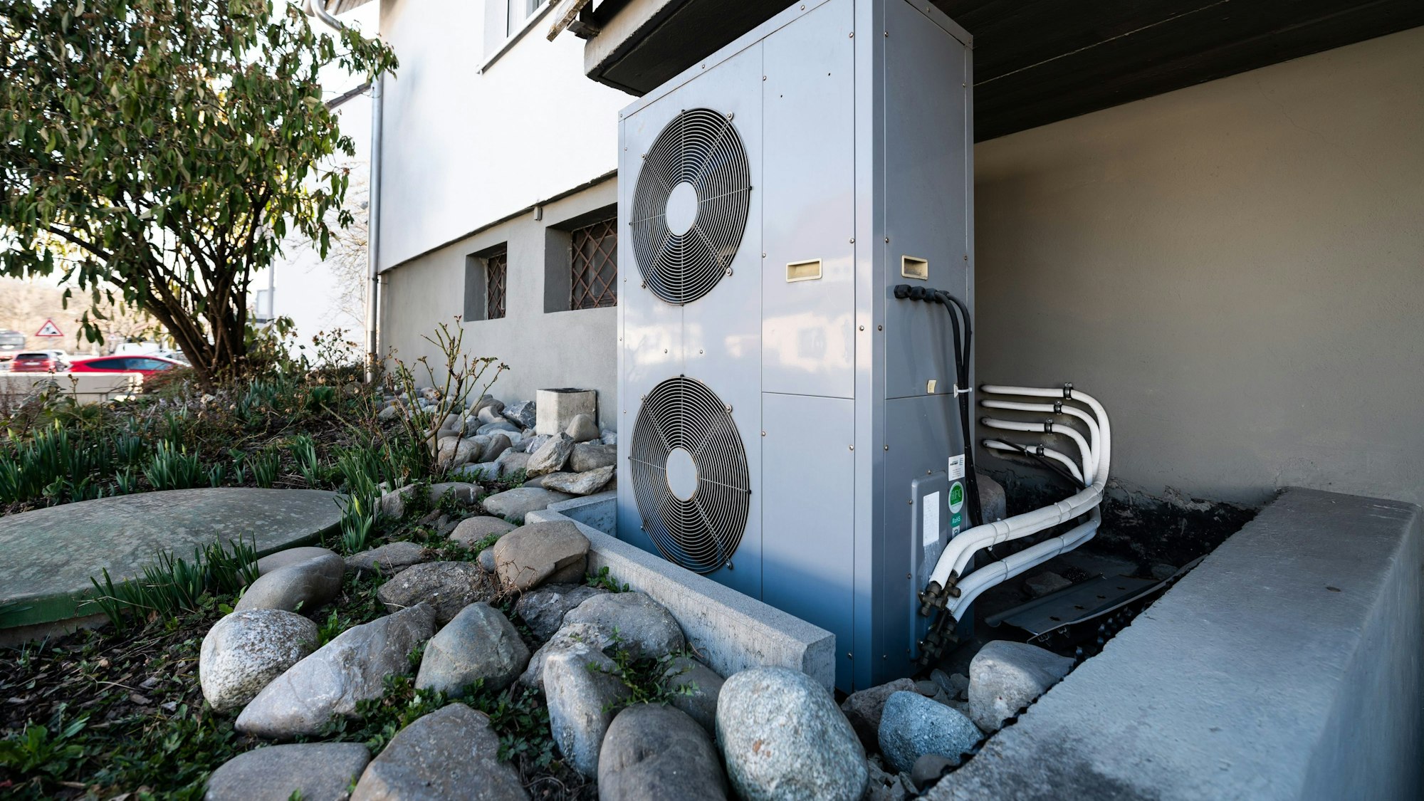 Die Lüftungsanlage einer Wärmepumpe steht vor einem Wohnhaus.