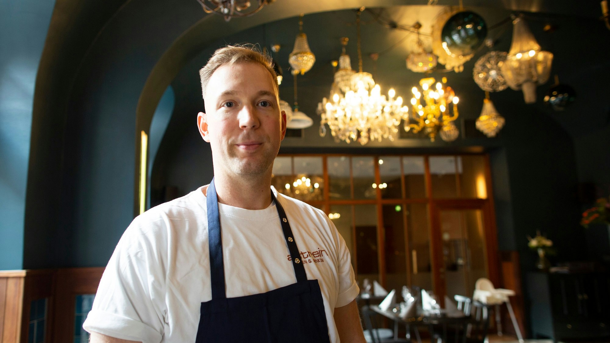 Eric Werner, Inhaber des „Astrein“, hier im „Augustin“, seinem zweiten Restaurant. An der Decke hängen verschiedenen Lampen und ein Kronleuchter.