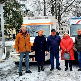 Drei Männer und zwei Frauen stehen vor zwei Rettungsfahrzeugen.