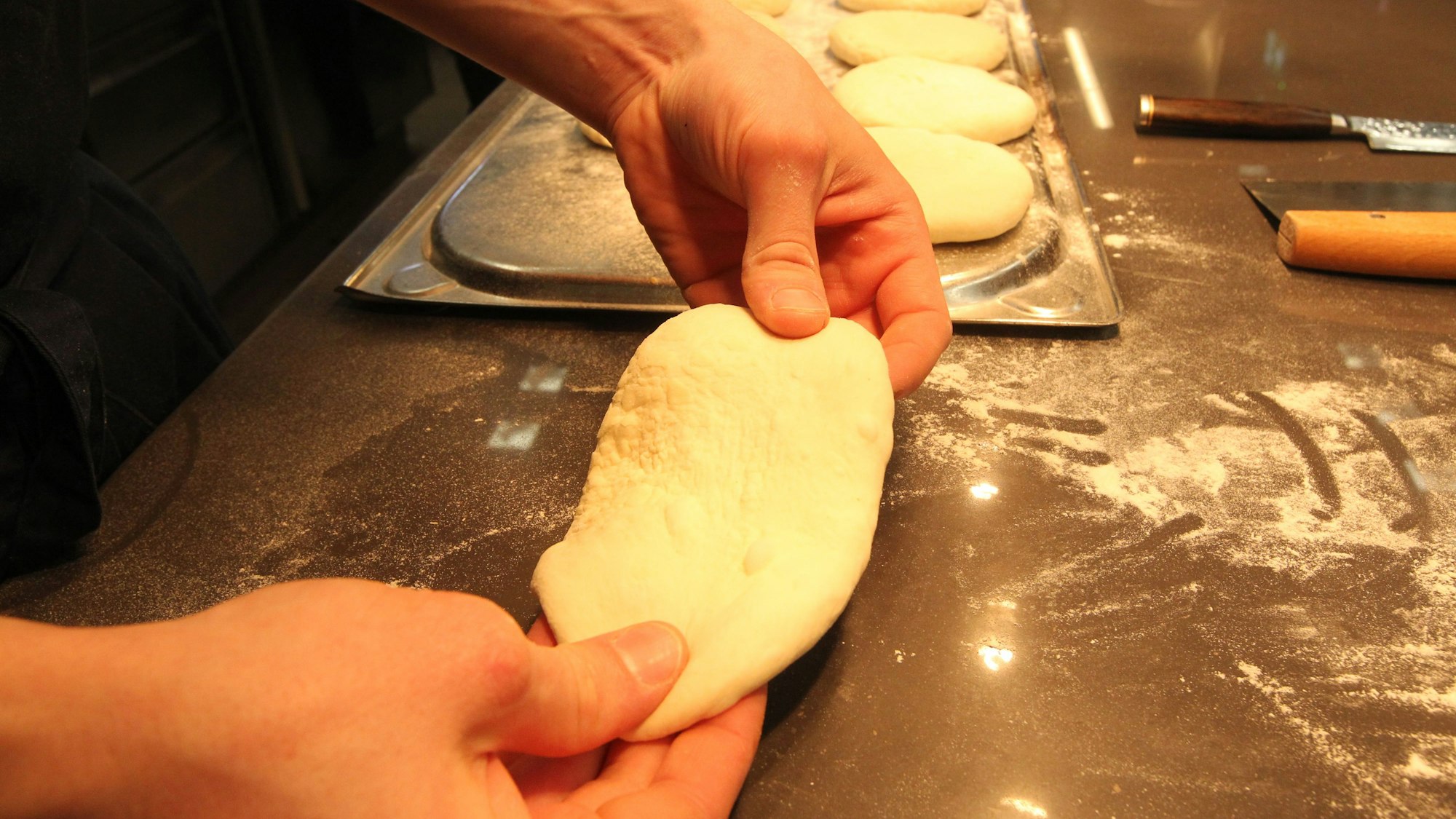 Zwei Hände kneten einen hellen Teig.