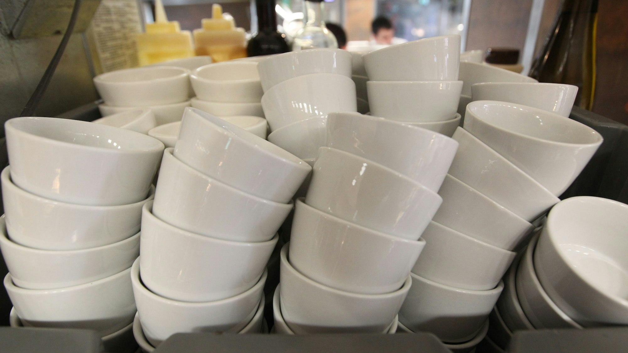 Weiße Dippschalen sind in einem Regal gestapelt.