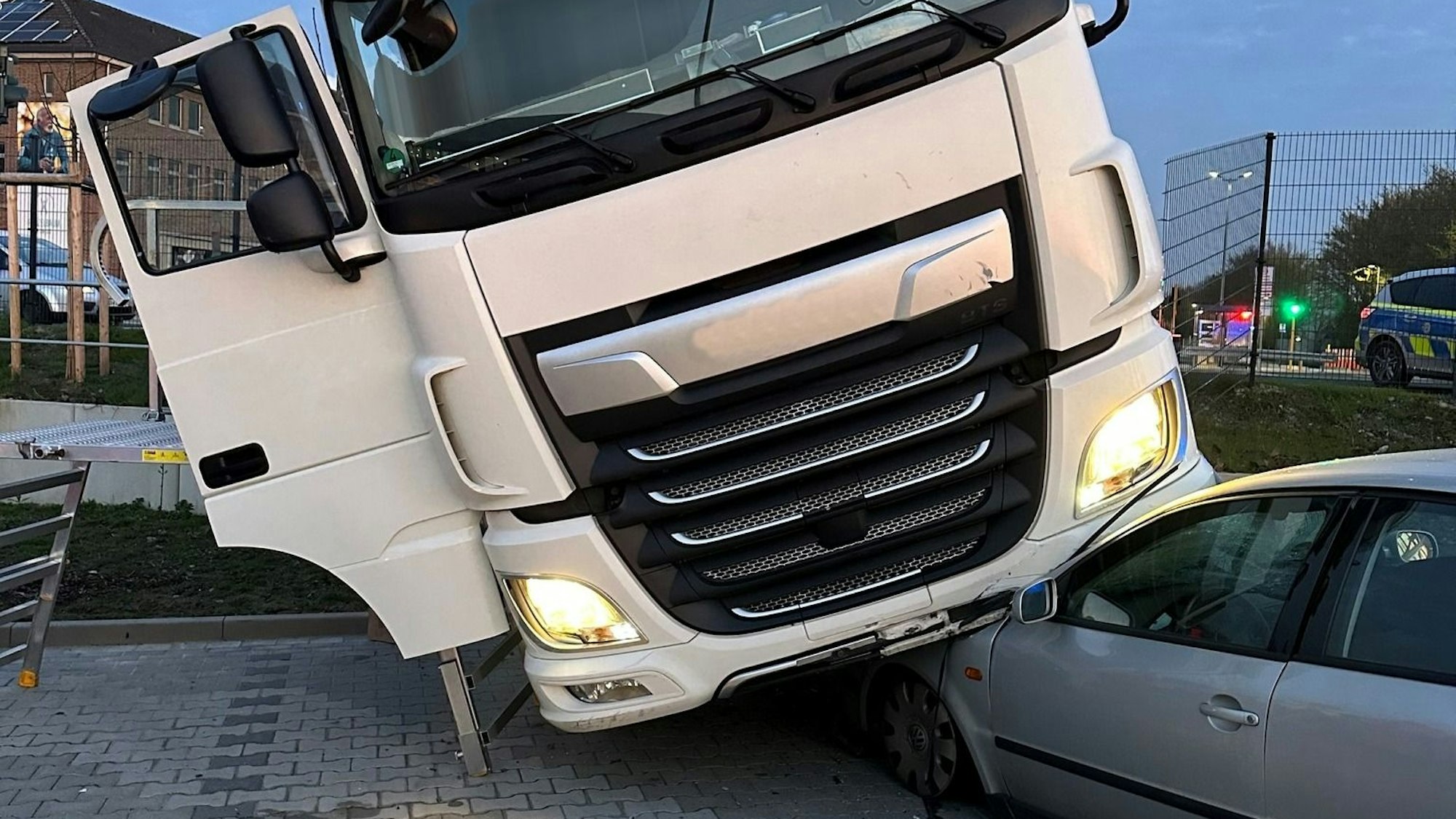 Die Zugmaschine eines Lkw-Sattelzugs steht auf der Motorhaube eines total beschädigten Pkw.