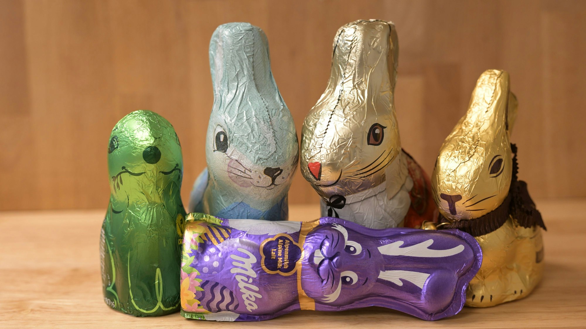 Die fünf noch verpackten Schokohasen stehen auf einem Tisch.