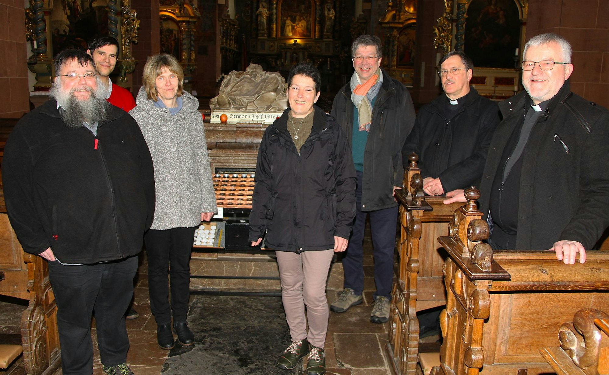 Das Pastoralteam um Wieslaw Kaczor (r.) steht am Grab des Eifel-Heiligen in der Steinfelder Basilika.