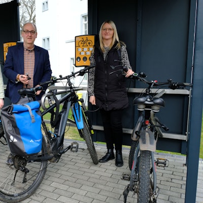 Zwei Männer und zwei Frauen stehen mit Fahrrädern an der E-Bike-Ladestation in Hellenthal.