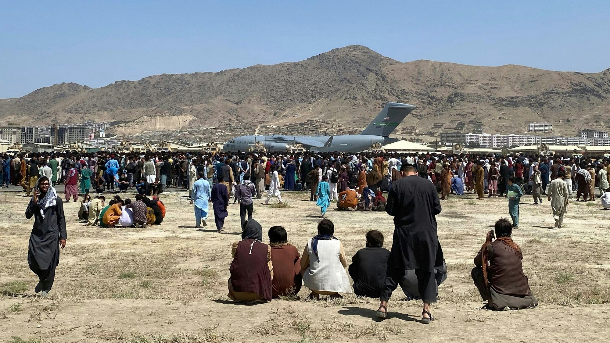 Menschen versammeln sich in der Nähe eines C-17-Transportflugzeugs der US-Luftwaffe auf dem Gelände des internationalen Flughafens in Kabul.