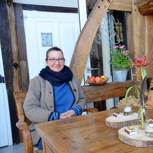 Eine Frau und ein Mann sitzen an einem Holztisch eines Cafés. Im Hintergrund sind Holzbalken zu sehen.
