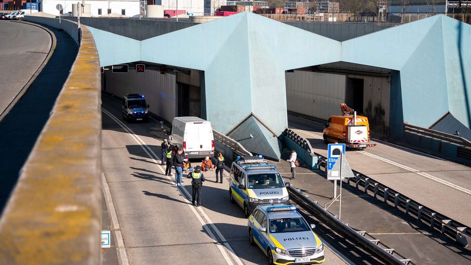 Klimaaktivisten haben sich auf der Fahrbahn der Autobahn 7 festgeklebt und blockieren so die Zufahrt des Elbtunnels in Richtung Norden. Foto: Daniel Bockwoldt/dpa +++ dpa-Bildfunk +++