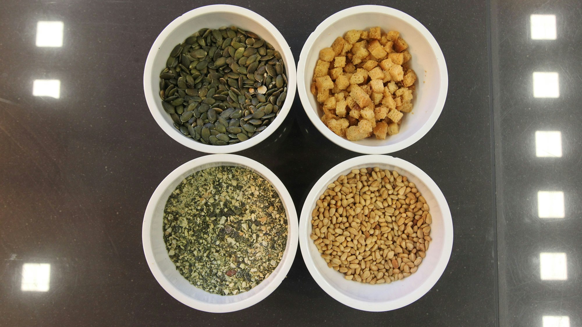 Vier weiße Schalen stehen auf einer Metalloberfläche.