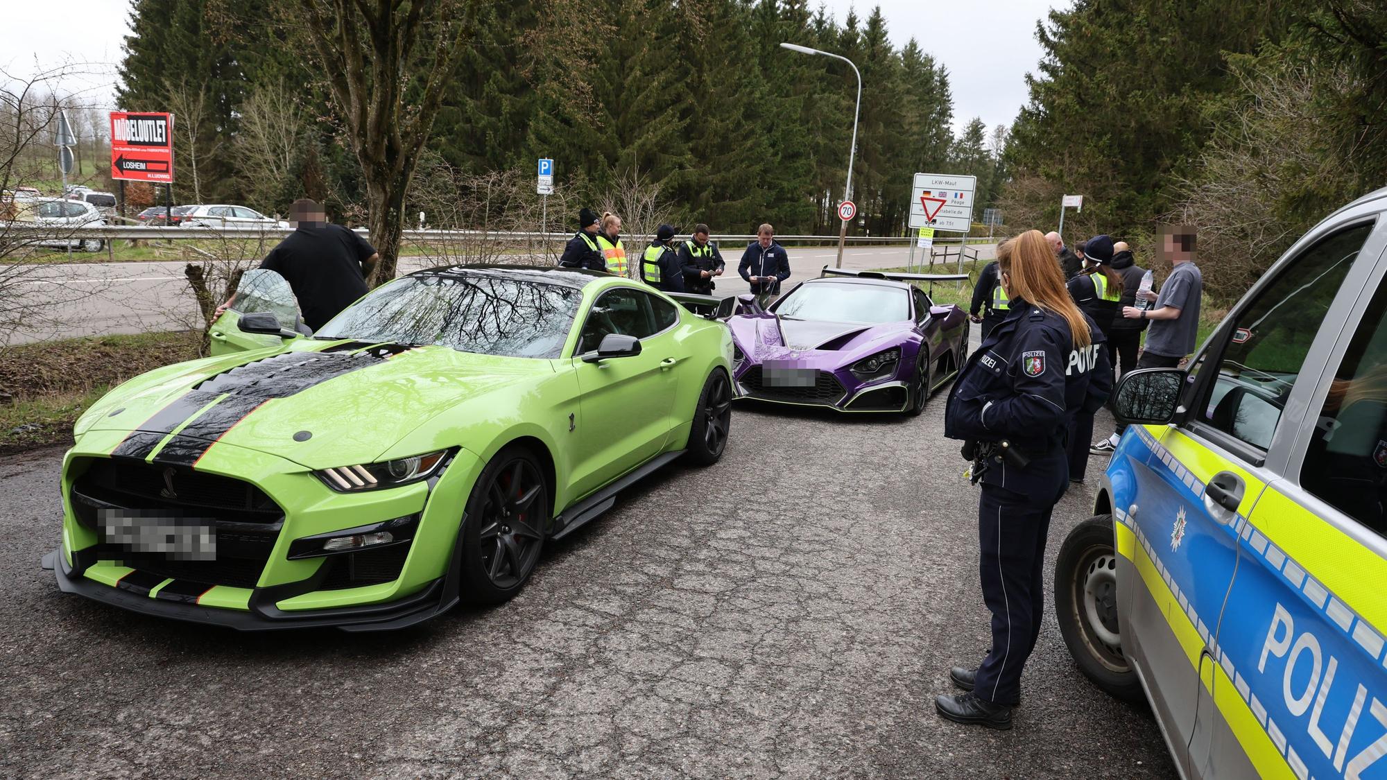 Zwei Sportwagen aus den Niederlanden sind von Polizisten herausgewunken worden und werden auf einem Parkplatz in Losheim kontrolliert.