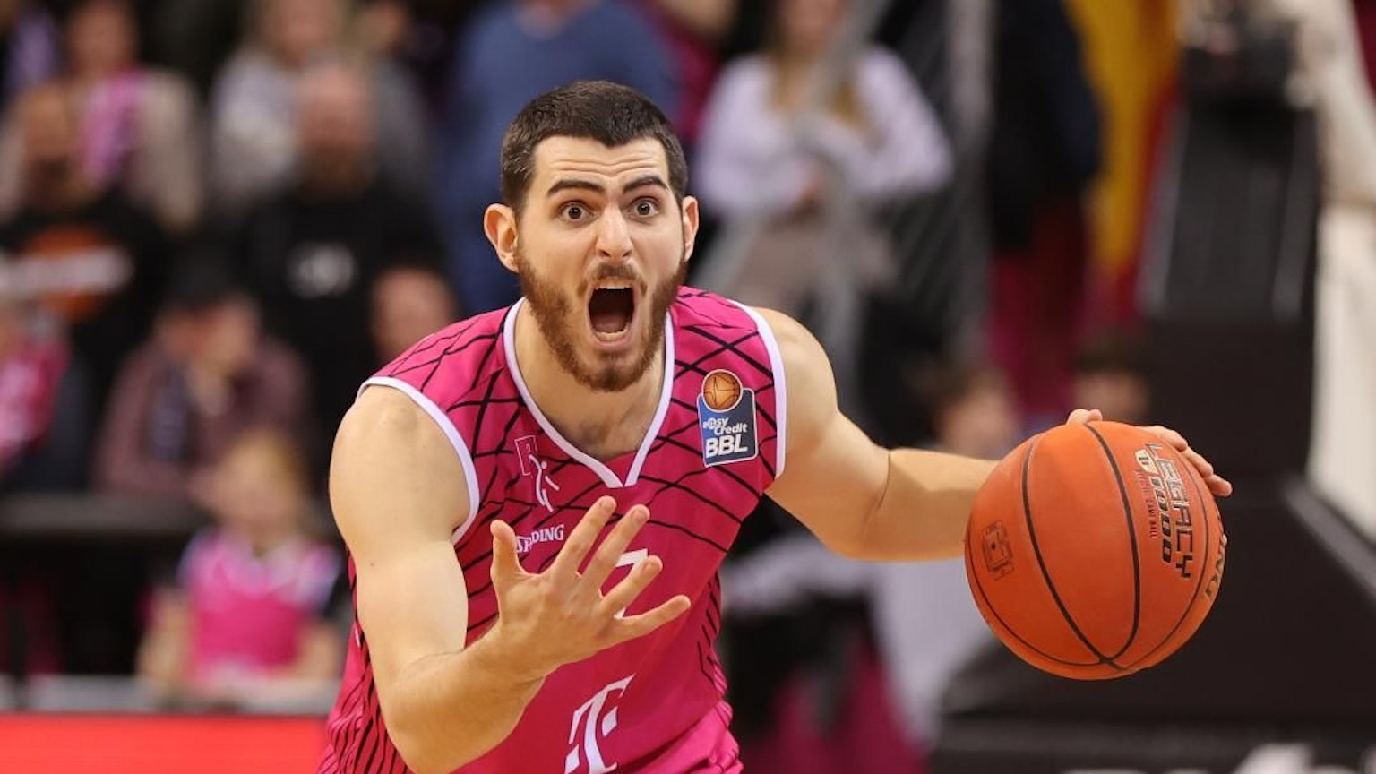 Sebastian Herrera im Telekom Baskets Laibchen schreit, mit Basketball in der Hand