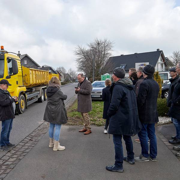 Während die Besucher am Straßenrand stehen, rollt ein Lastwagen mit Anhänger auf dem Mittelstreifen durch den Ort