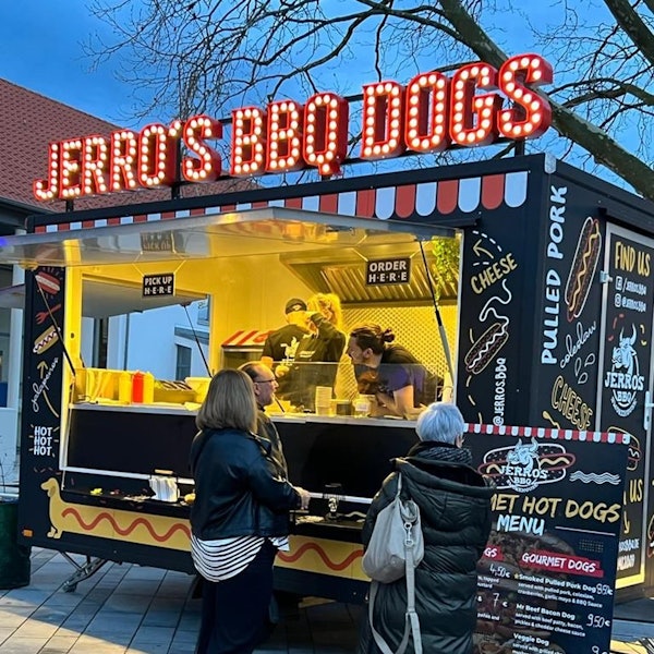 Es ist ein Streetfood-Wagen zu sehen, vor dem mehrere Leute stehen.