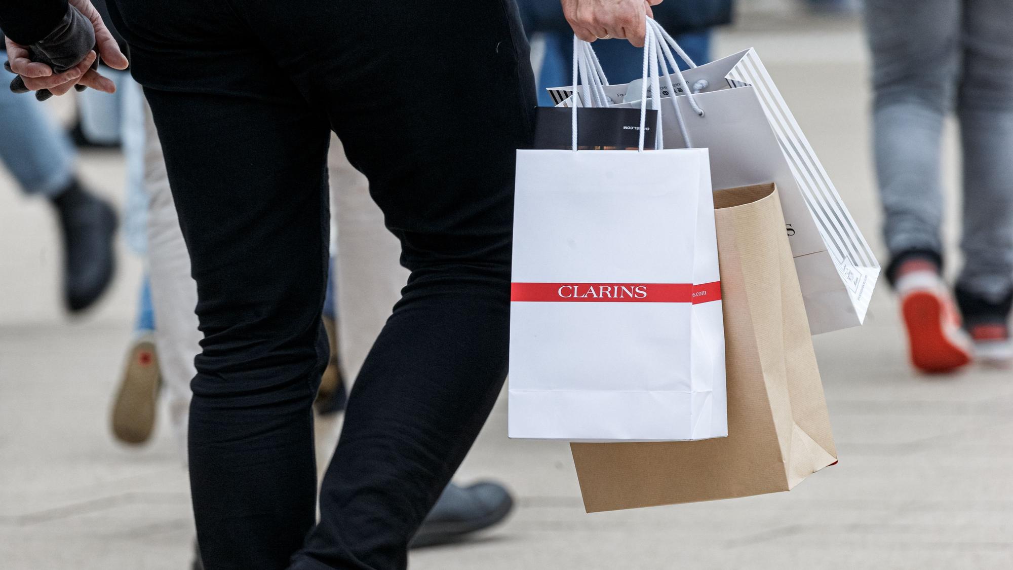 Ein Mann geht mit Einkaufstüten durch eine Innenstadt.