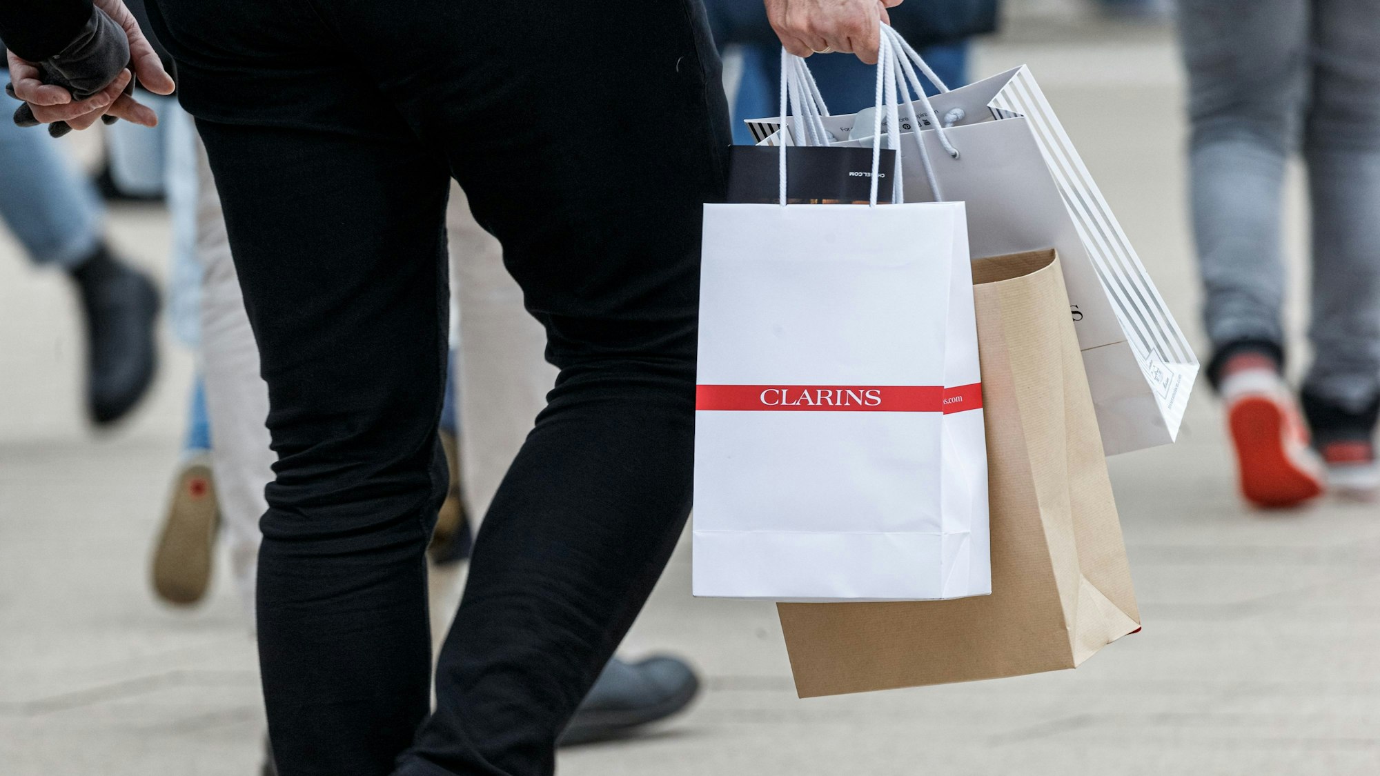 Ein Mann geht mit Einkaufstüten durch eine Innenstadt.