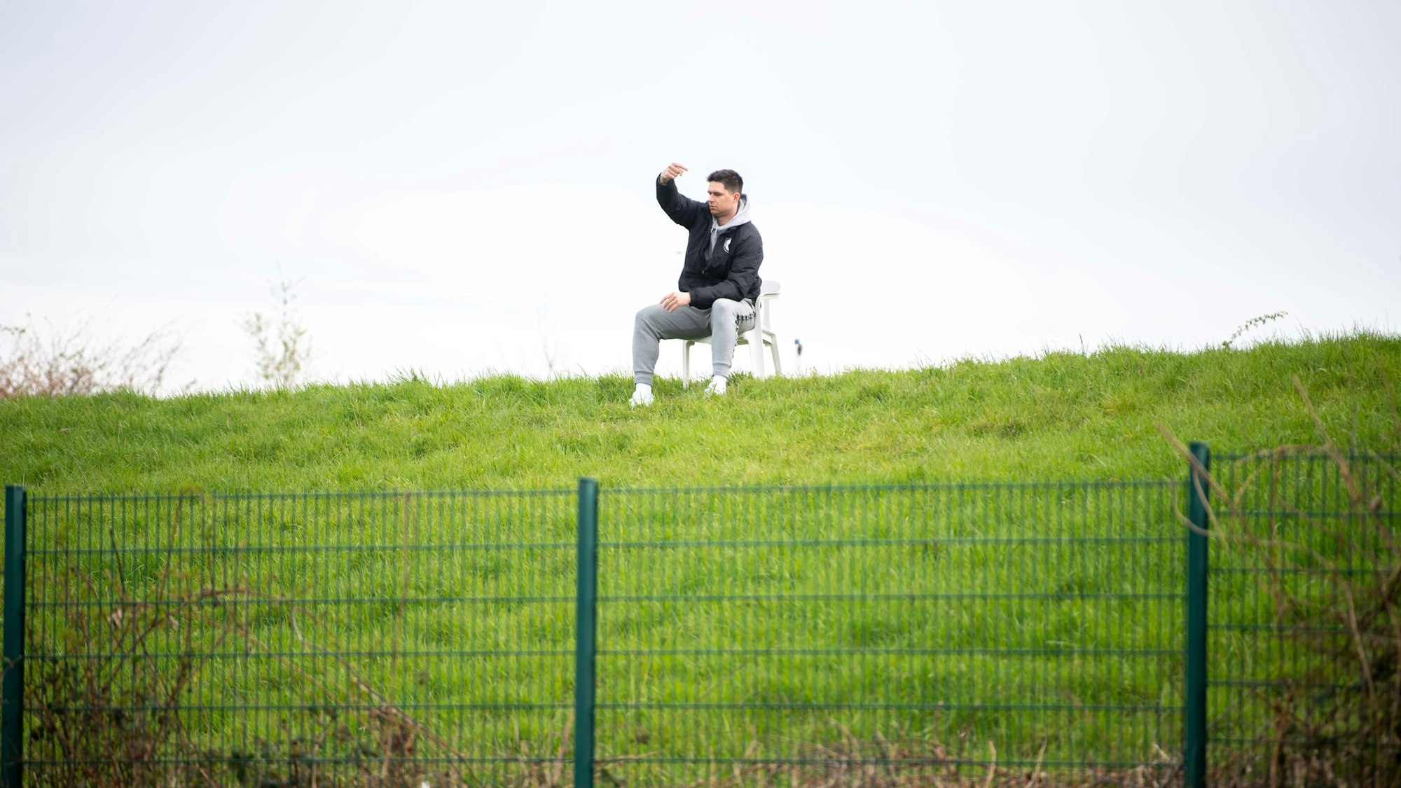 Der Trainer der Sportfreunde Wüschheim-Büllesheim, Lucas Carell, sitzt auf einer Anhöhe und gibt seinem Team Anweisungen.