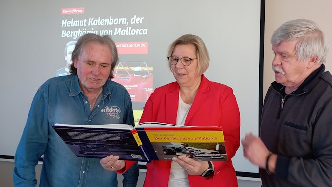 3.4.2023 Stöbern zur Ankündigung des Films über den aus Straßfeld stammenden Rennfahrer Helmut Kalenborn in dem Buch von Jörg-Thomas Födisch (r.): Bürgermeisterin Petra Kalkbrenner und Karl-Heinz Peters
