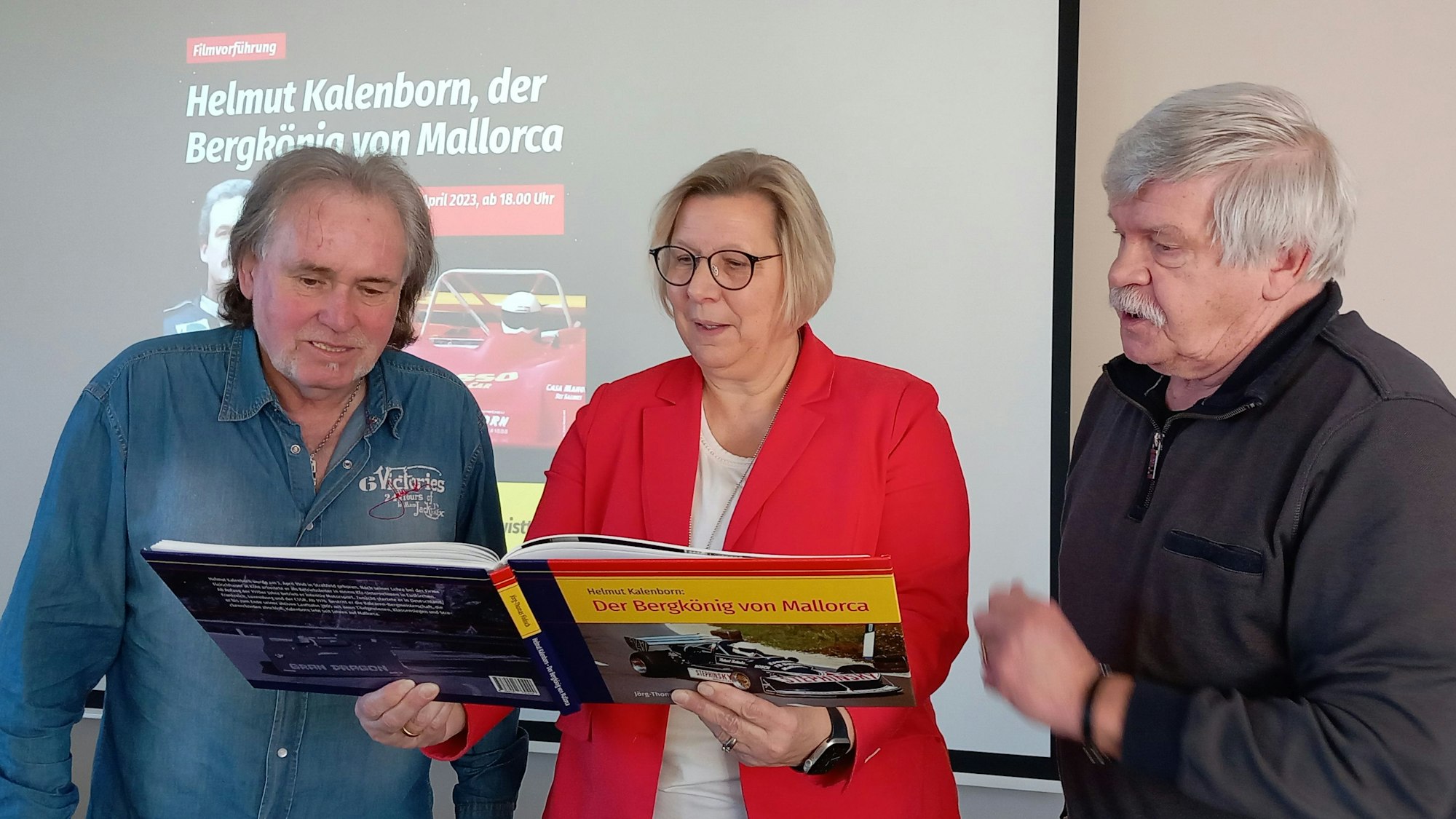 3.4.2023 Stöbern zur Ankündigung des Films über den aus Straßfeld stammenden Rennfahrer Helmut Kalenborn in dem Buch von Jörg-Thomas Födisch (r.): Bürgermeisterin Petra Kalkbrenner und Karl-Heinz Peters