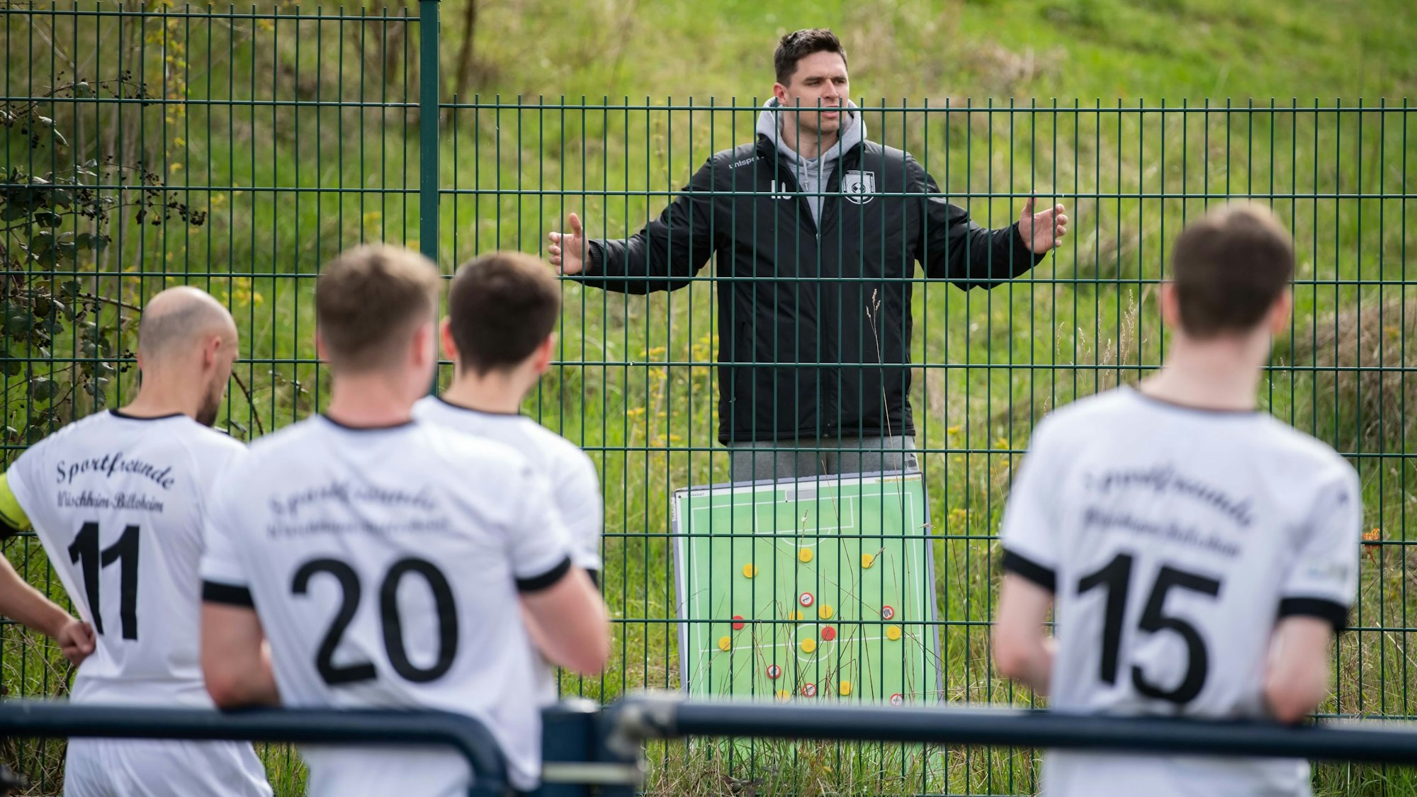 Hinter Gittern: Trainer Lucas Carell hält Abstand und gibt in der Halbzeit taktische Anweisung hinter dem grünen Zaun, der um den Kunstrasenplatz gezogen worden ist.