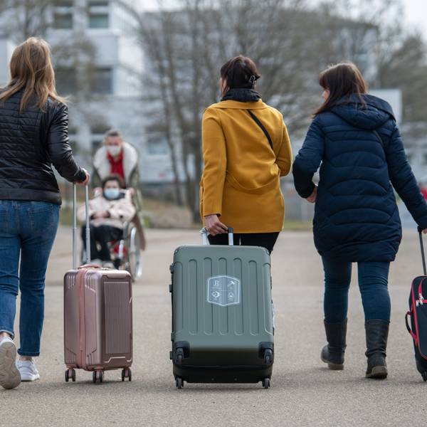 Mit Koffern erreichen Geflüchtete eine Unterbringungseinrichtung.