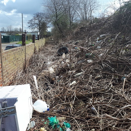 Eine alte Waschmaschine, Plastikkanister, Autoreifen und sonstiger Unrat türmt sich hinter einer Bahndamm-Mauer an der Etzelstraße.