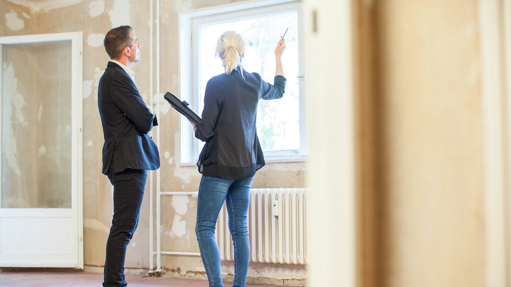 Eine Immobilienmaklerin zeigt einem Interessenten eine Wohnung.