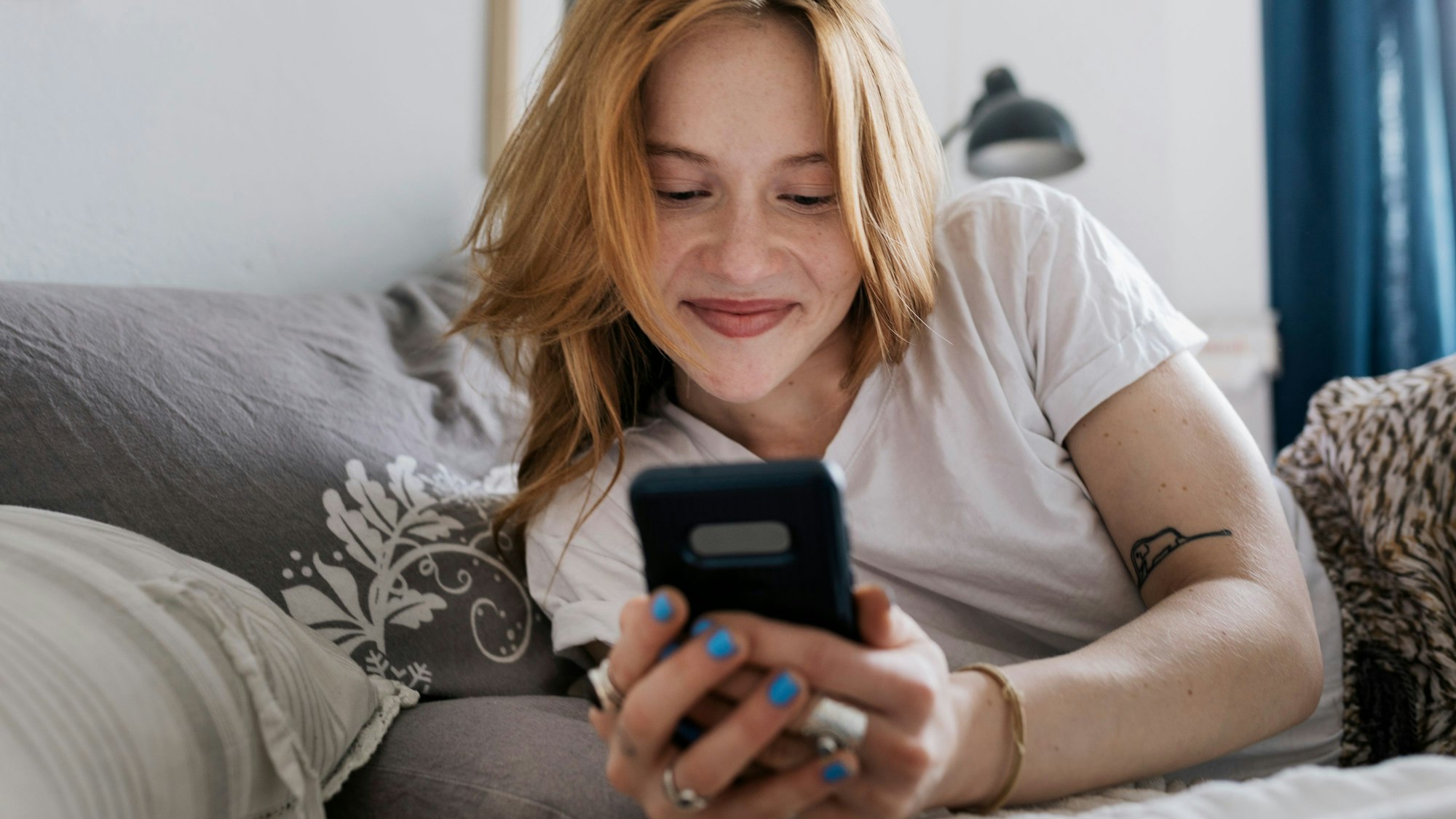 Frau auf dem Bett mit Handy in der Hand