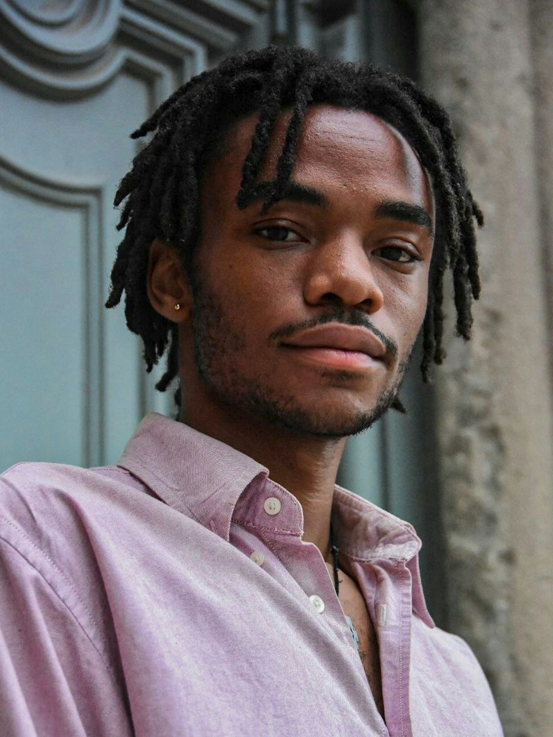 Logan February, ein junger Schwarzer Mann mit kurzen Dreadlocks, schaut in die Kamera.