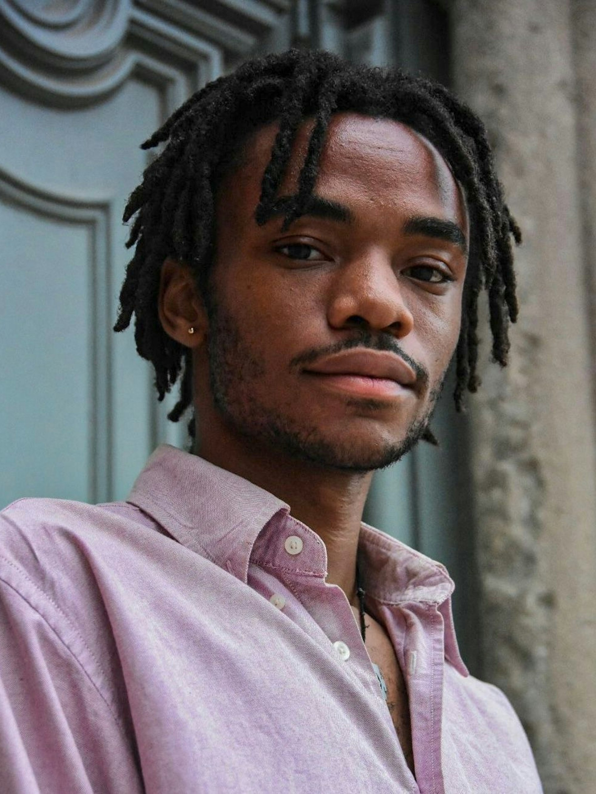 Logan February, ein junger Schwarzer Mann mit kurzen Dreadlocks, schaut in die Kamera.