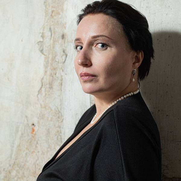 Kateryna Kalytko, eine weiße Fra mittleren Alters mit kurzen dunklen Haaren schaut über ihre Schulter in die Kamera.