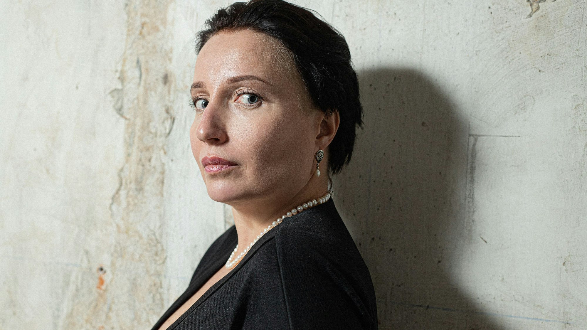 Kateryna Kalytko, eine weiße Fra mittleren Alters mit kurzen dunklen Haaren schaut über ihre Schulter in die Kamera.