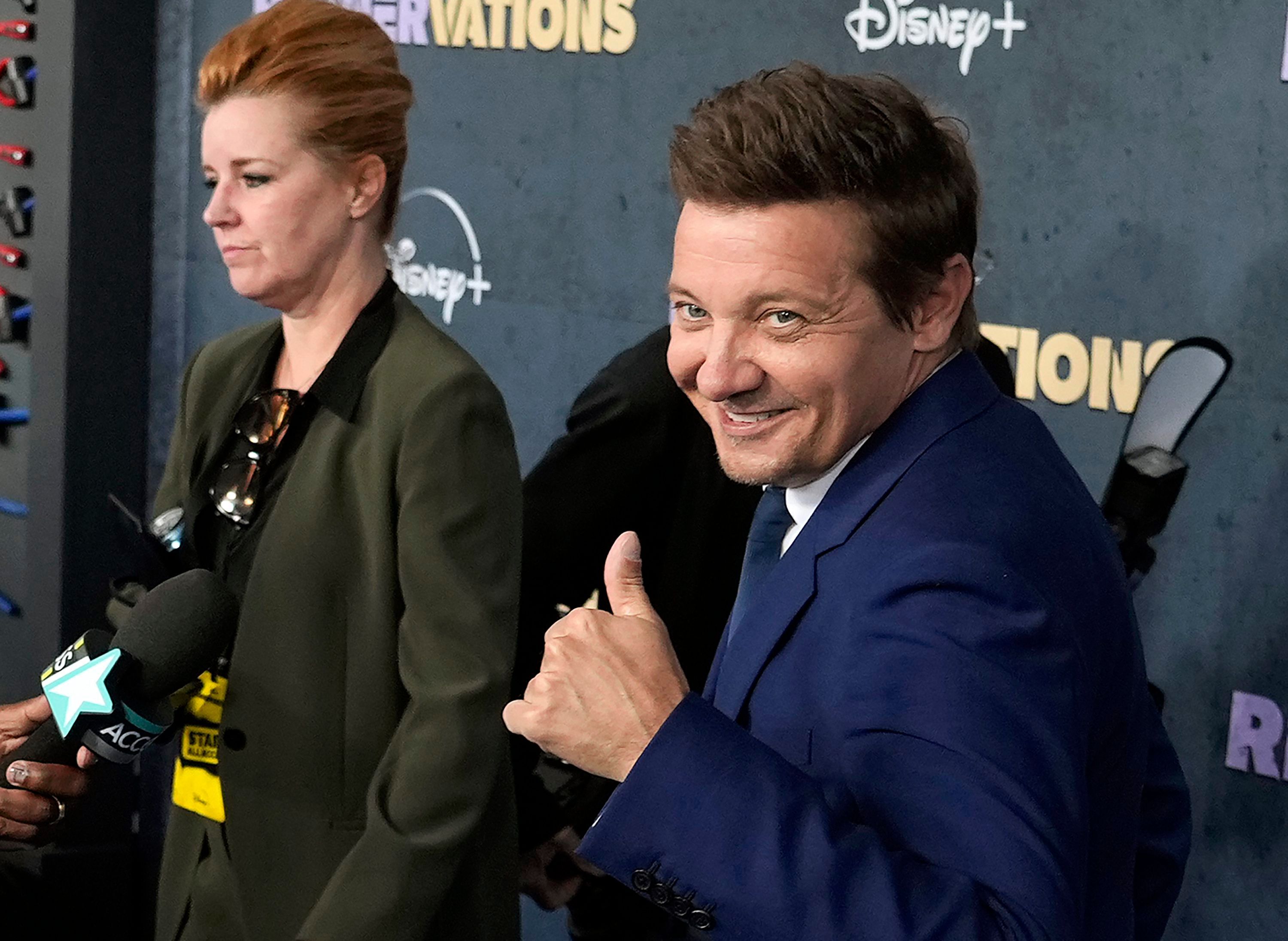 Jeremy Renner hält seinen Daumen hoch und guckt in die Kamera.
