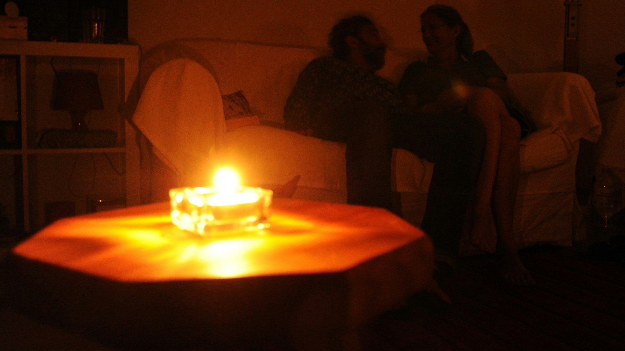 Ein Paar sitzt während eines Stromausfalls bei Kerzenschein in einer Wohnung in Hannover.