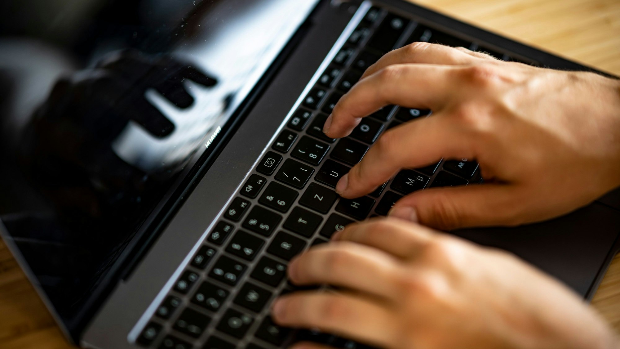 Ein Mann tippt auf einer Tastatur eines Laptops.