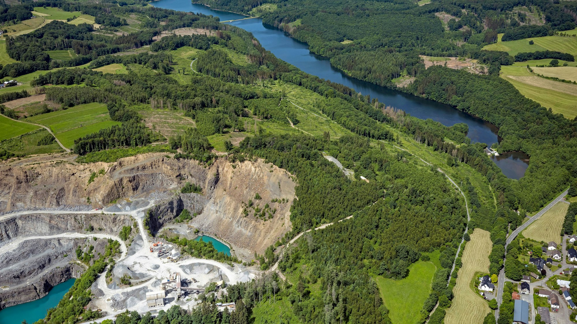 Eine Luftaufnahme zeigt die Wiehltalsperre und viele Bäume. Vor den Bäumen liegt ein Abhang.