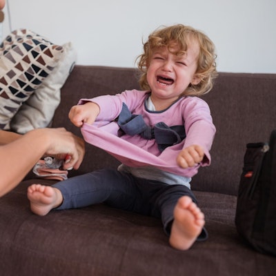 Ein Kleinkind schreit, weil es sich nicht anziehen möchte.