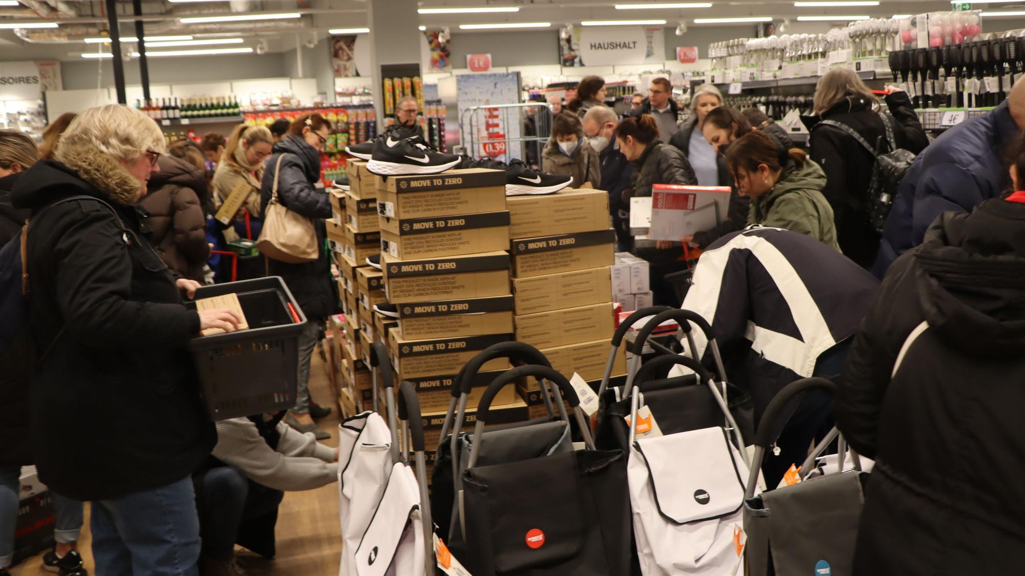 Viele Menschen stehen um einen Verkaufstisch mit Schuhen und Taschen.