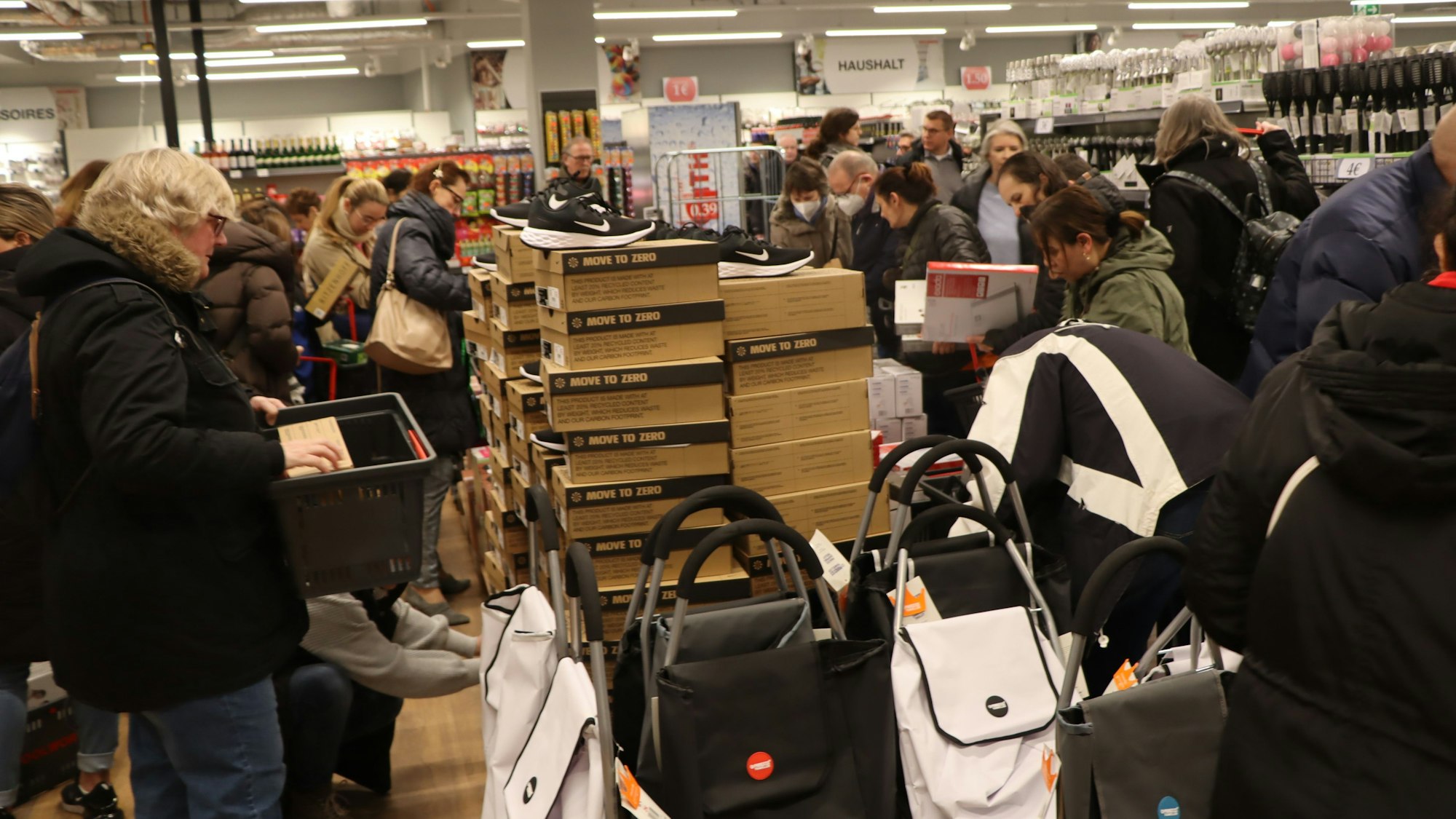 Viele Menschen stehen um einen Verkaufstisch mit Schuhen und Taschen.