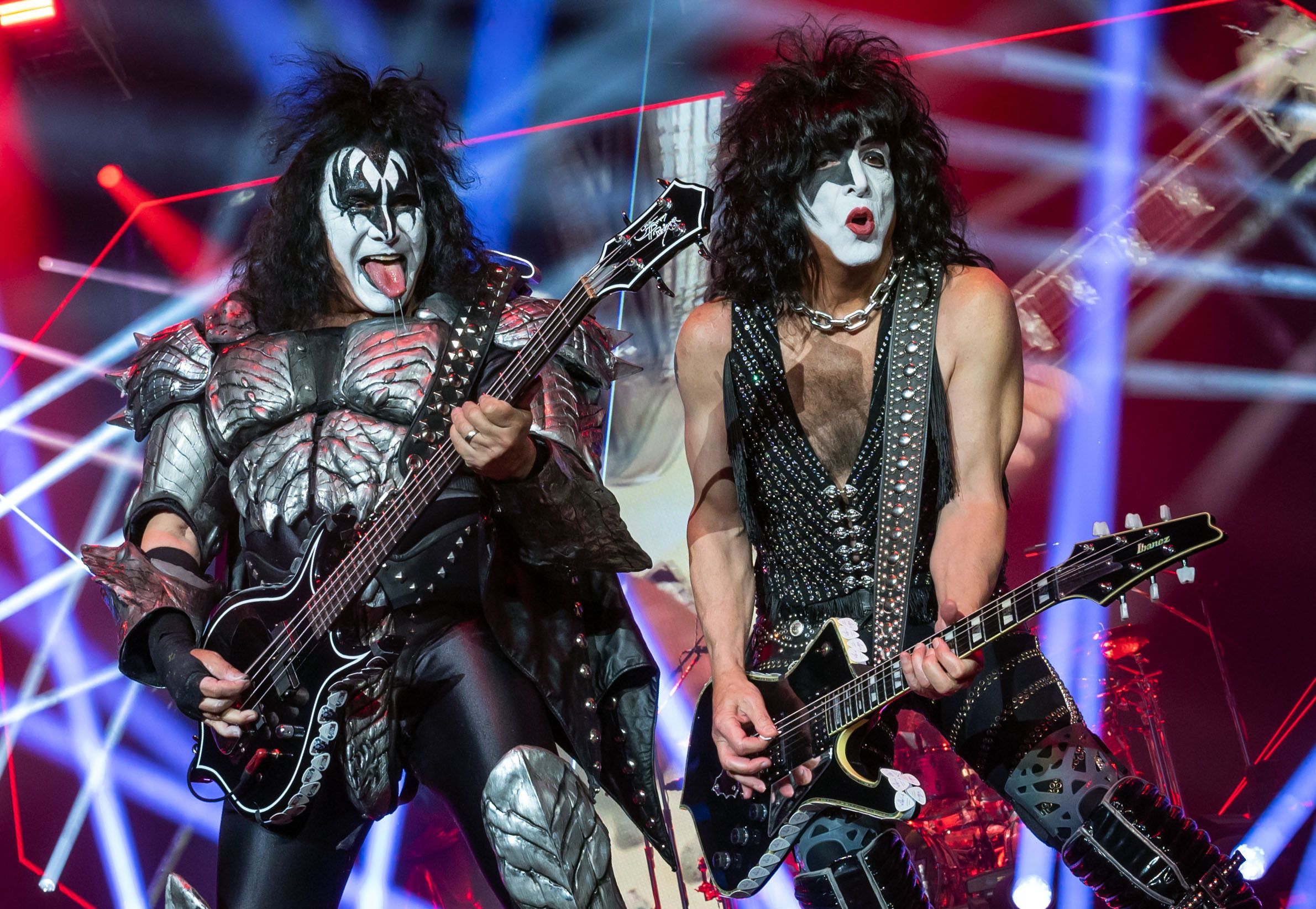 Gene Simmons und Paul Stanley von der US-amerikanischen Hard-Rock-Band Kiss bei einem Auftritt auf der Bühne. Sie halten E-Gitarren in der Hand.