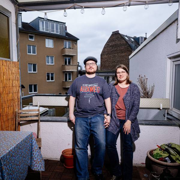 Ein Paar steht auf seinem Balkon.