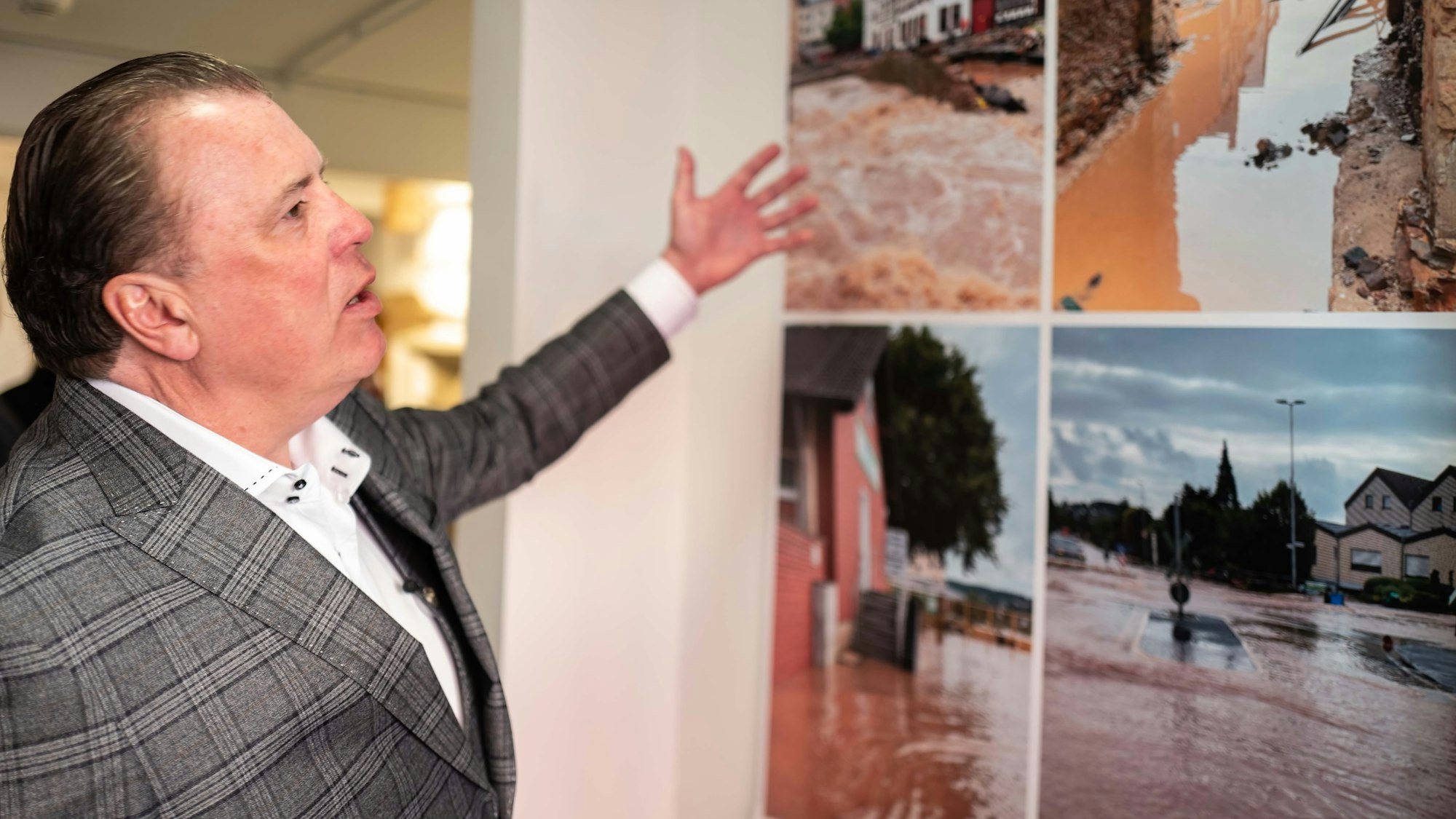 Marc Brucherseifer, Geschäftsführer des City Outlets, deutet auf einige Bilder, die nach der Flutkatastrophe in Bad Münstereifel entstanden sind.